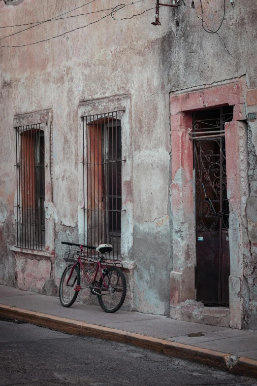 a bike is parked in front of a building, inspired by Steve McCurry, pexels contest winner, tlaquepaque, faded red colors, color”