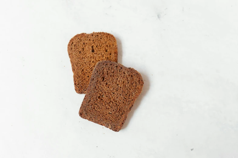 two slices of bread on a white surface, inspired by Richmond Barthé, unsplash, hurufiyya, dark brown, sandstone, 6 pack, 4yr old