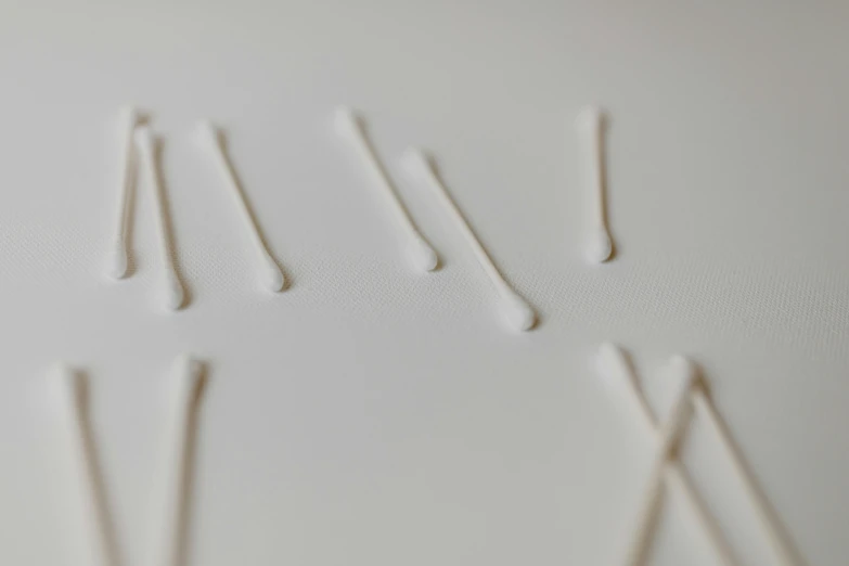 a pile of toothpicks sitting on top of a white table, inspired by Lucio Fontana, unsplash, process art, nasal strip, silver，ivory, roman numerals, bumps