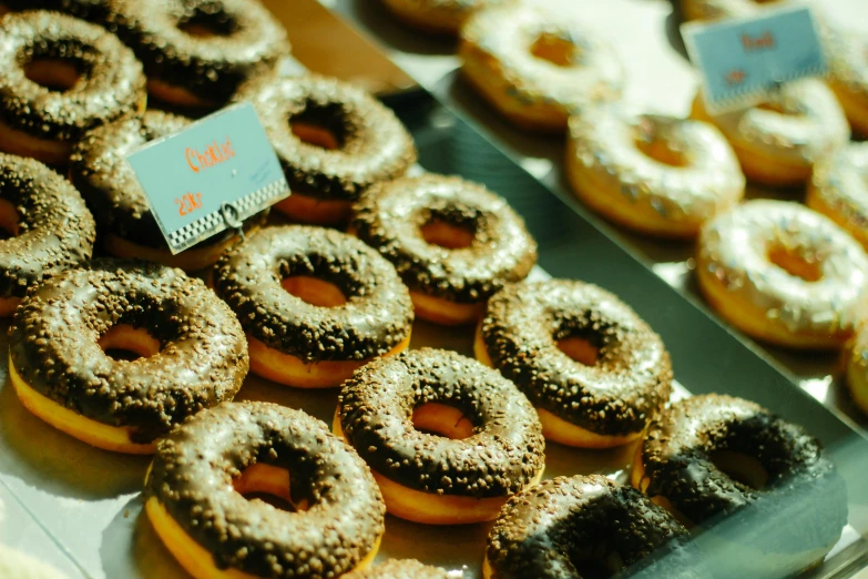 a display case filled with lots of different kinds of donuts, pexels, hurufiyya, sparkling in the sunlight, brown, animation, caulfield