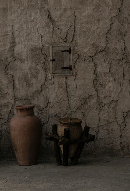 a couple of vases sitting next to a wall, pexels contest winner, cauldrons, low quality photo, cracked walls, full frame image