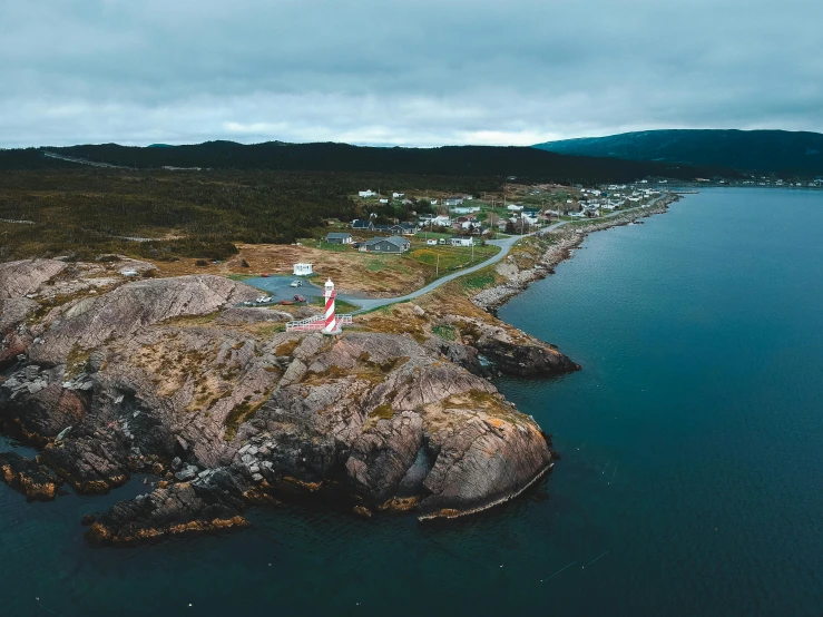 a lighthouse sitting on top of a rock next to a body of water, happening, flatlay, quebec, hills and ocean, whealan