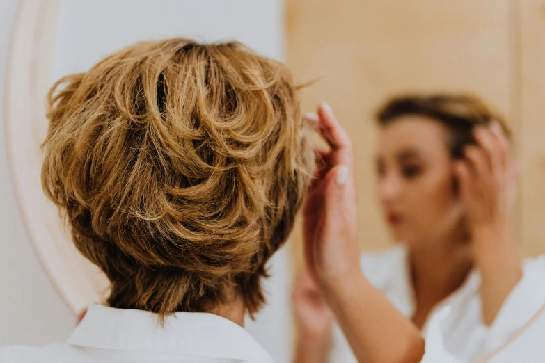 a woman putting her hair in front of a mirror, trending on pexels, fantastic realism, short blond hair, doctors mirror, profile image, half image