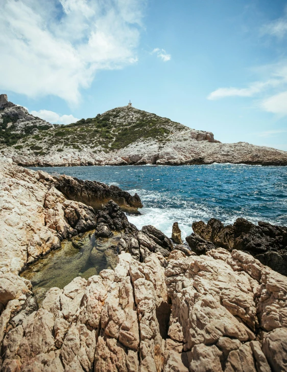 a large body of water sitting on top of a rocky beach, by Raphaël Collin, pexels contest winner, les nabis, over a calanque, slide show, slightly tanned, low quality photo