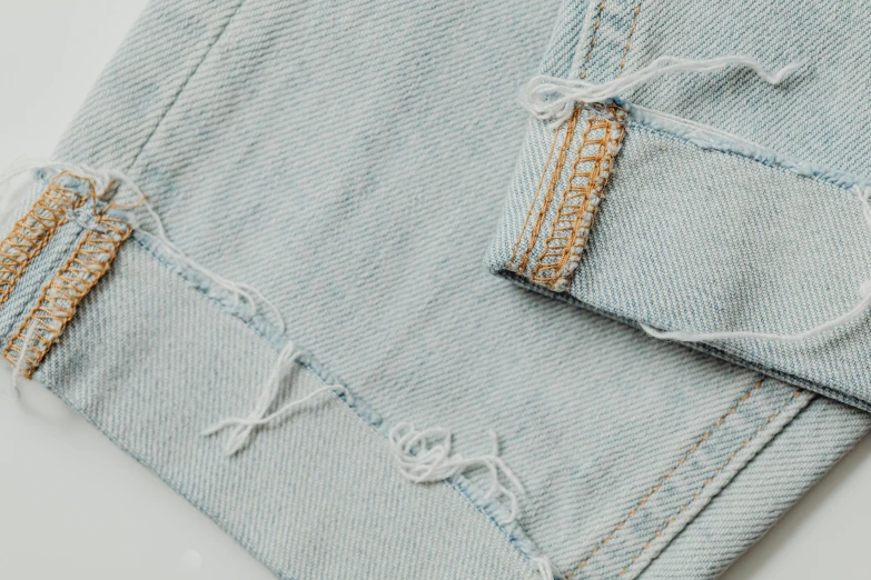 a pair of jeans sitting on top of a table, inspired by Elsa Bleda, trending on pexels, visual art, seamless micro detail, ripped fabric, detached sleeves, detail shot