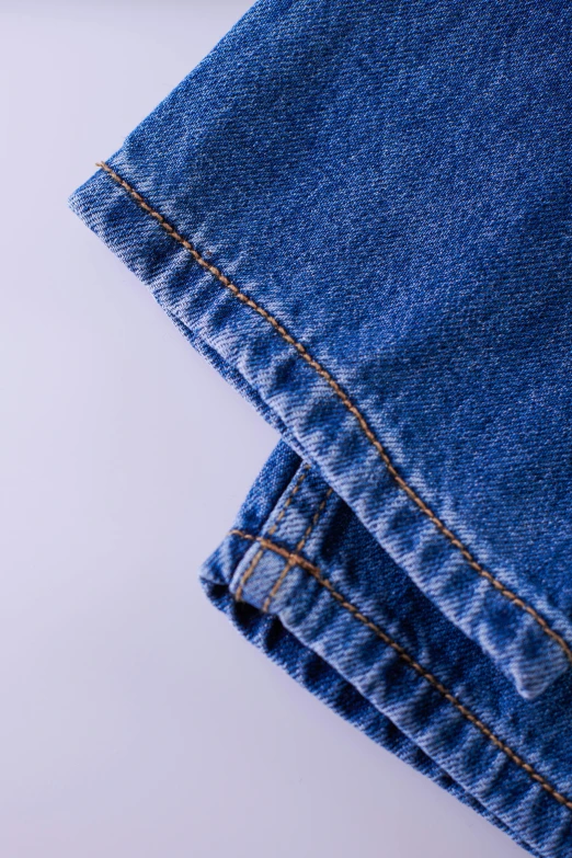a pair of jeans folded on top of each other, by Reuben Tam, trending on unsplash, seamless micro detail, detailed product image, the dress\'s lower, high definition image