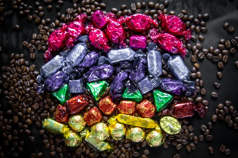 a pile of chocolates sitting on top of a pile of coffee beans, by Joe Bowler, instagram, rainbow colours, foil, thumbnail, grape