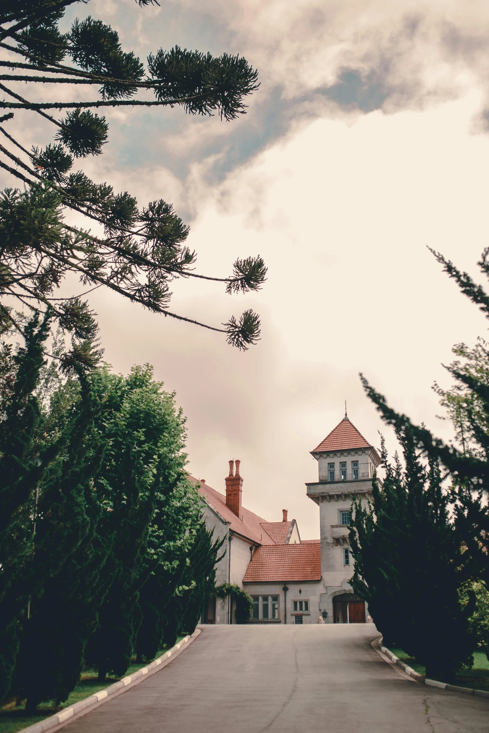 a large white house sitting on the side of a road, unsplash, art nouveau, lookout tower, low quality photo, red roofs, stormy day