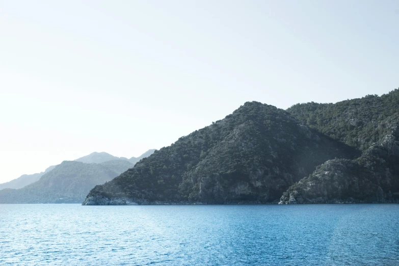 a large body of water with mountains in the background, by Exekias, pexels contest winner, hurufiyya, blueish tones, mediterranean, multiple stories, picton blue