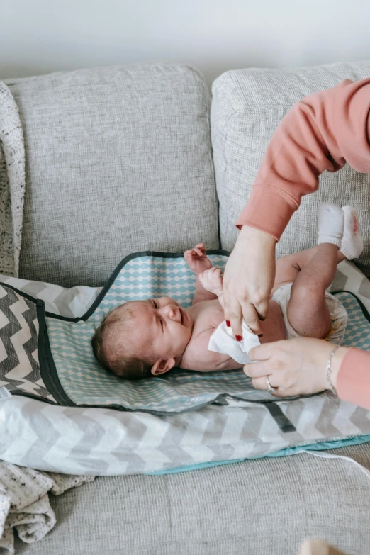 a woman sitting on a couch holding a baby, pexels contest winner, happening, first aid kit, square, dry skin, demo scene