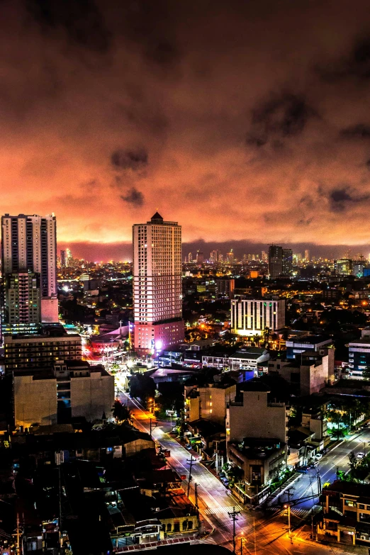 an aerial view of a city at night, by Robbie Trevino, pexels contest winner, happening, manila, sunset panorama, apocalyptic, with dramatic sky