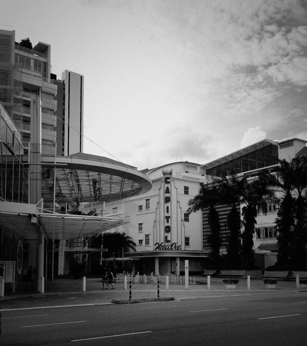 a black and white photo of a city street, unsplash, brutalism, singapore esplanade, manly, cinema still, rounded architecture
