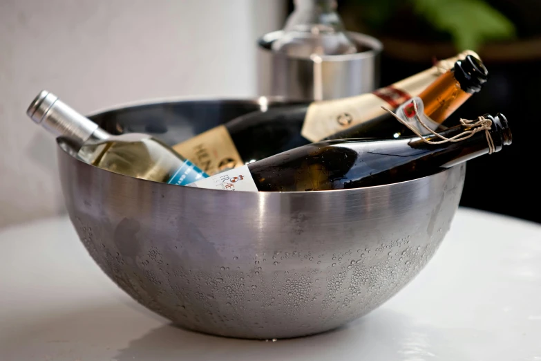 a silver bowl filled with bottles of wine, inspired by Charles Le Roux, bubbles everywhere, stone ocean, made of brushed steel, freezing