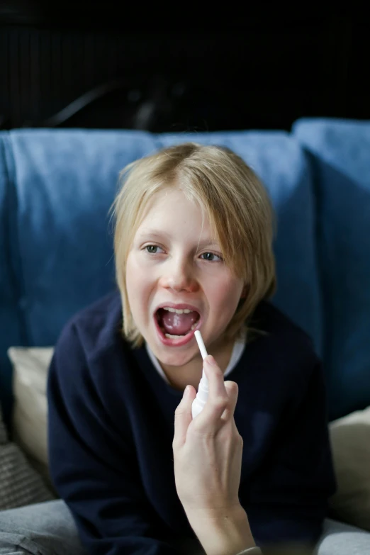 a woman sitting on a couch brushing her teeth, by Sven Erixson, pexels, happening, boy with neutral face, lips wide parted, portrait of small, holding syringe