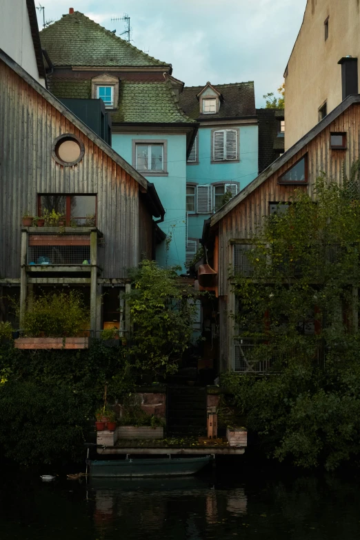 a couple of buildings that are next to a body of water, inspired by Carl Spitzweg, unsplash, renaissance, wooden houses, kreuzberg, lush garden surroundings, grey
