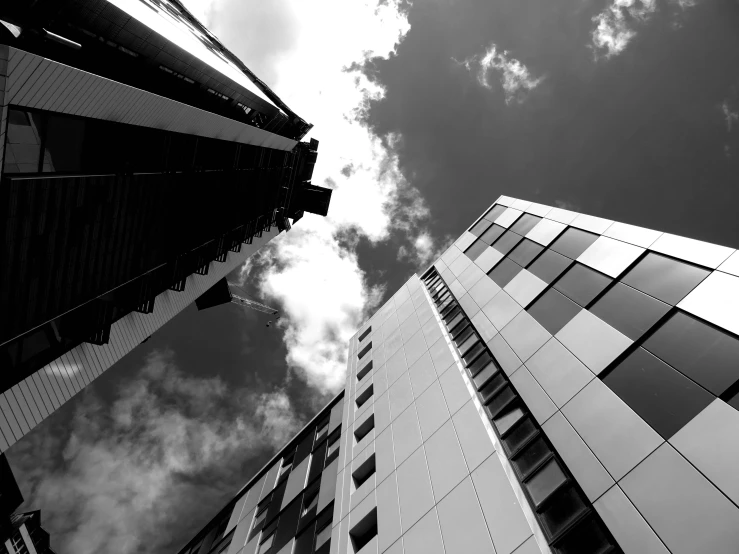 a couple of tall buildings sitting next to each other, a black and white photo, by Dave Allsop, tectonic sky, photographic print