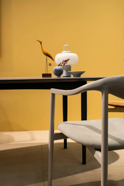 a chair sitting next to a table in a room, an abstract sculpture, inspired by Constantin Hansen, colors: yellow, rosenthal, intracate detail, ikebana