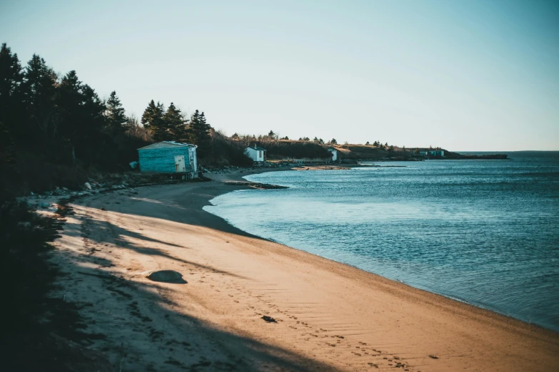 a sandy beach next to a body of water, by Carey Morris, pexels contest winner, cottage town, inuit heritage, maple syrup sea, retro vibe