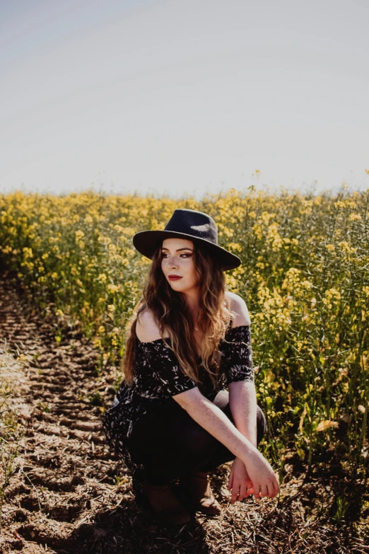 a woman sitting in a field of yellow flowers, pexels contest winner, black fedora, sydney sweeney, promotional image, casual black clothing