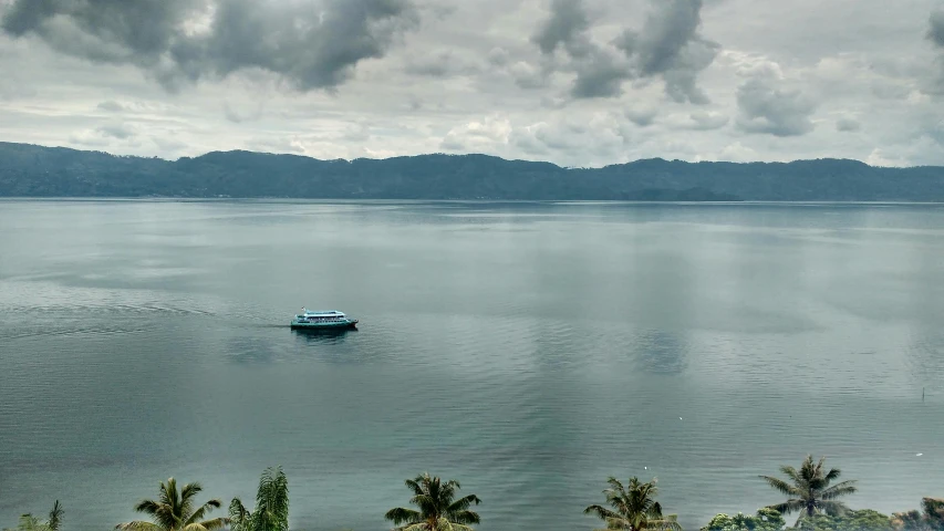 a boat floating on top of a large body of water, by Kogan Gengei, pexels contest winner, sumatraism, panorama distant view, shades of blue and grey, slide show, overcast