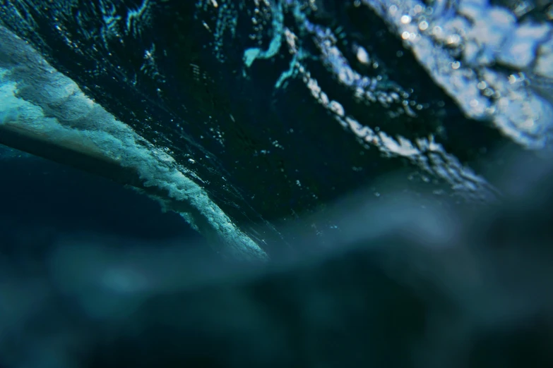 a penguin swimming under a wave in the ocean, a picture, pexels contest winner, the blue whale crystal texture, 4 k hd film still, blurred, teal aesthetic