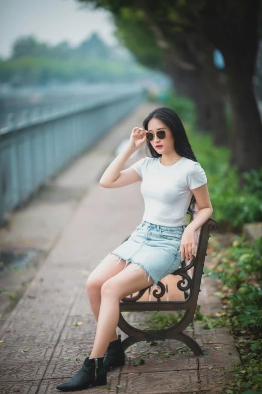 a woman sitting on top of a wooden bench, by Raymond Han, pexels contest winner, realism, dressed in a white t-shirt, dang my linh, full body cute young lady, with sunglass