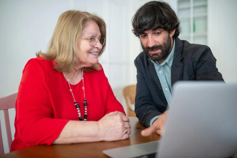 a man and woman sitting at a table looking at a laptop, eliezer yudkowsky, avatar image, professional shot, spanish