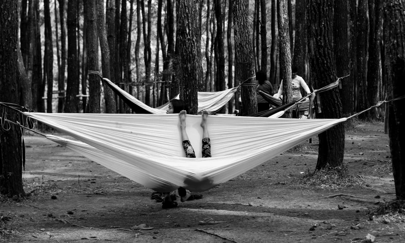 a black and white photo of a person laying in a hammock, by Dariusz Zawadzki, pexels contest winner, forest picnic, extreme panoramic, oyasumi punpun, sport