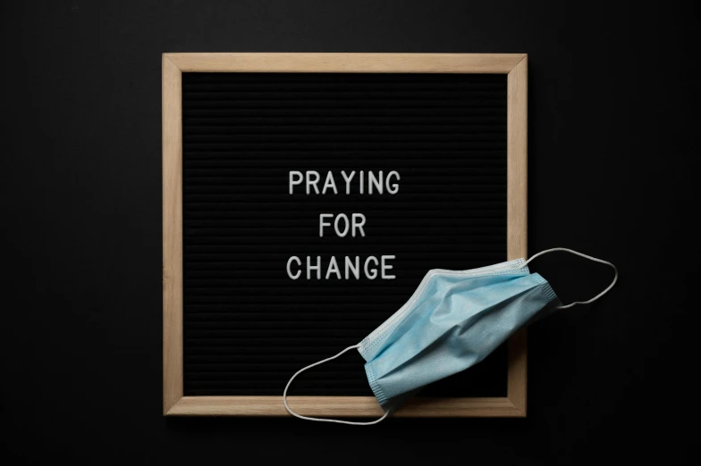 a mask on top of a sign that says praying for change, trending on pexels, hurufiyya, 1 6 x 1 6, on a dark background, hospital, filling the frame