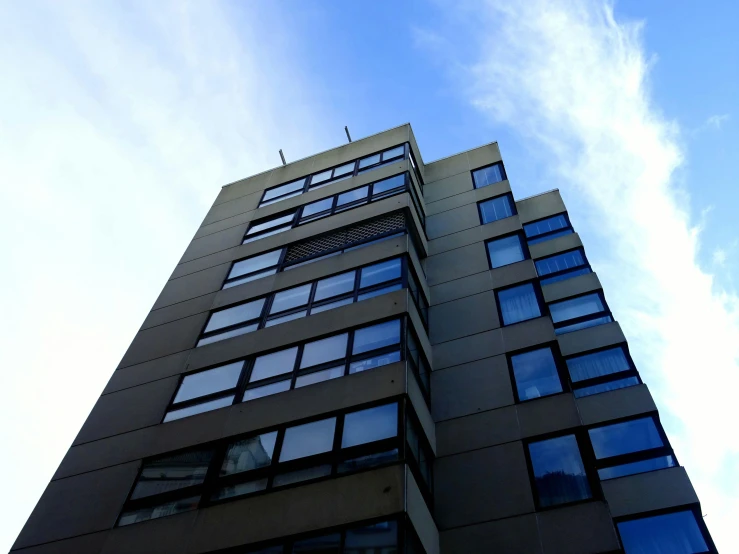 a very tall building with lots of windows, inspired by Richard Wilson, unsplash, brutalism, clear blue sky, low quality photo, full daylight, low angle!!!!