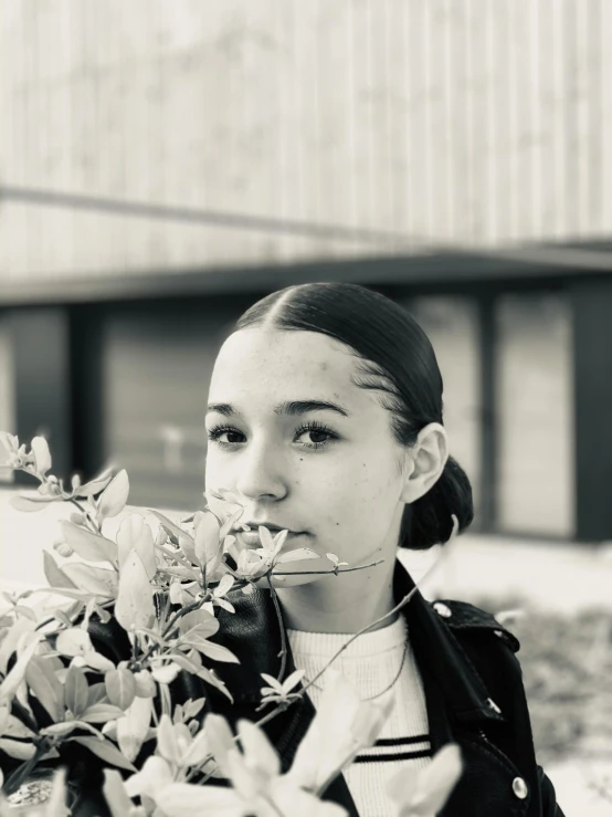 a woman holding a bunch of flowers in front of a building, a black and white photo, unsplash, realism, portrait of ariana grande, 🤤 girl portrait, greta thunberg, alexandria ocasio-cortez