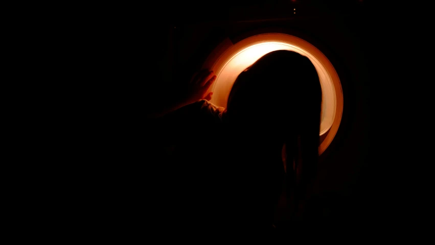 a person that is standing in the dark, looking at us from a porthole, clamp shell lighting, pottery, warm orange lighting