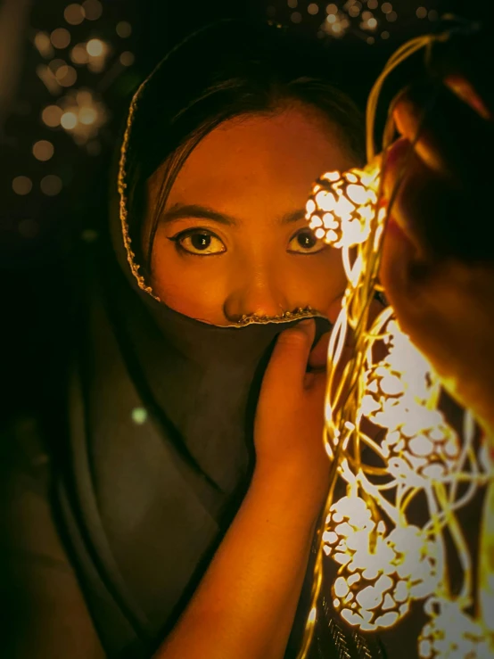 a woman holding a flower in front of her face, inspired by Steve McCurry, unsplash contest winner, glowing lights intricate elegant, muslim, ✨🕌🌙, a young asian woman