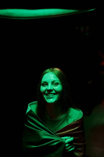 a woman that is standing in the dark, vivid green lasers, while smiling for a photograph, kirsi salonen, bright green dark orange