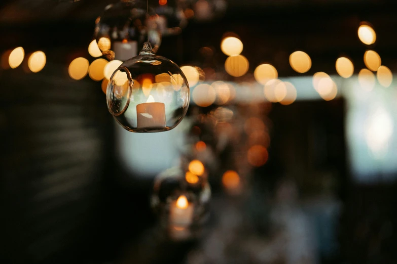 a bunch of lights hanging from a ceiling, trending on unsplash, light and space, on a candle holder, hanging out with orbs, bokeh photo, candlelit restaurant table