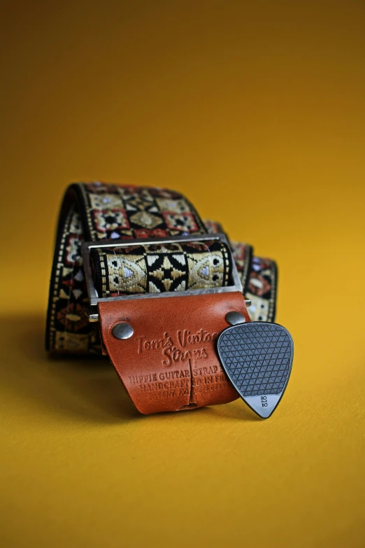 a guitar strap with a guitar pick in it, inspired by Wes Wilson, unsplash contest winner, folk art, leather belt, highly ornate, checkered motiffs, detailed surroundings
