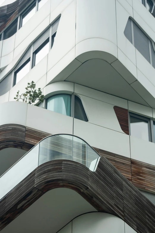 a very tall building with a lot of windows, an abstract sculpture, inspired by Zaha Hadid, unsplash, plants on balconies, hoog detail, terraced, large overhangs