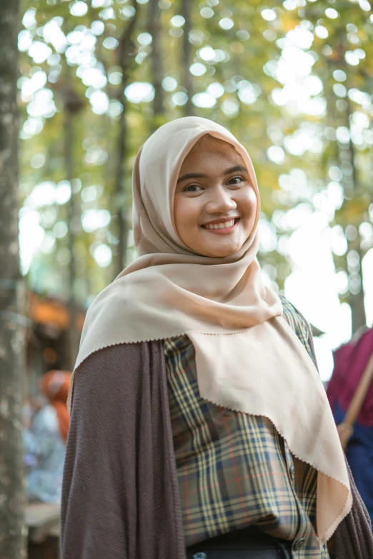 a woman in a hijab smiles at the camera, hurufiyya, in a forest, wearing casual clothing, fair complexion, wearing authentic attire