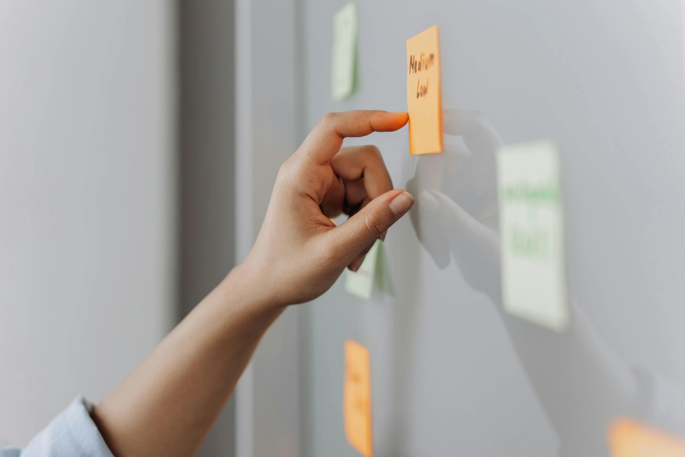 a person standing in front of a whiteboard with sticky notes on it, by Emma Andijewska, pexels contest winner, closeup of hand, developers, on a gray background, magnetic