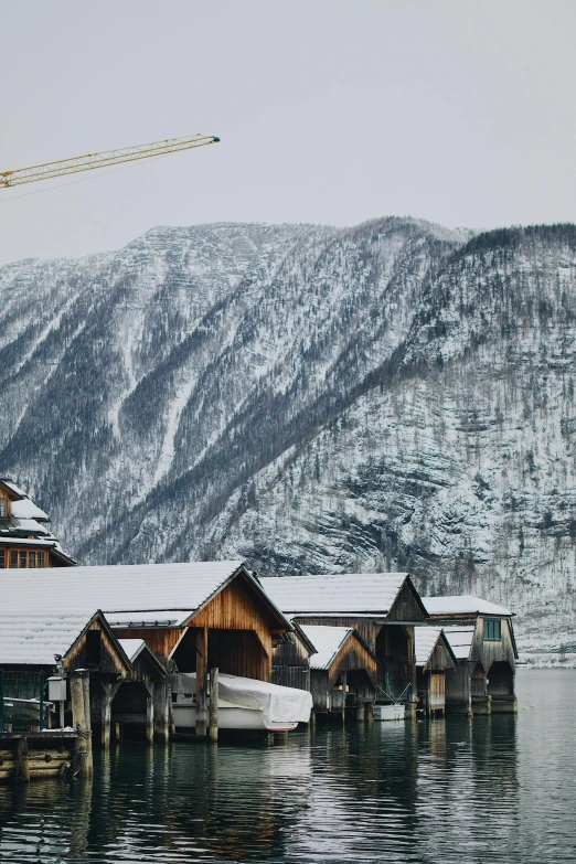 a body of water surrounded by snow covered mountains, inspired by Peter Zumthor, houses on stilts, slovakia, gondolas, exterior photo