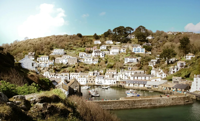 a town sitting on top of a hill next to a body of water, by Julian Hatton, pexels contest winner, several cottages, dean cornwall, conde nast traveler photo, slightly sunny