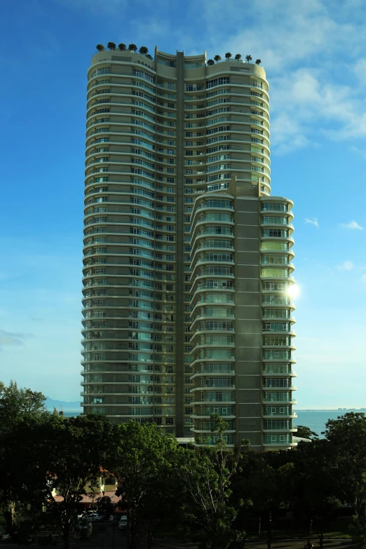 a couple of tall buildings sitting on top of a lush green field, in a beachfront environment, circular towers, exterior view, swirled architecture