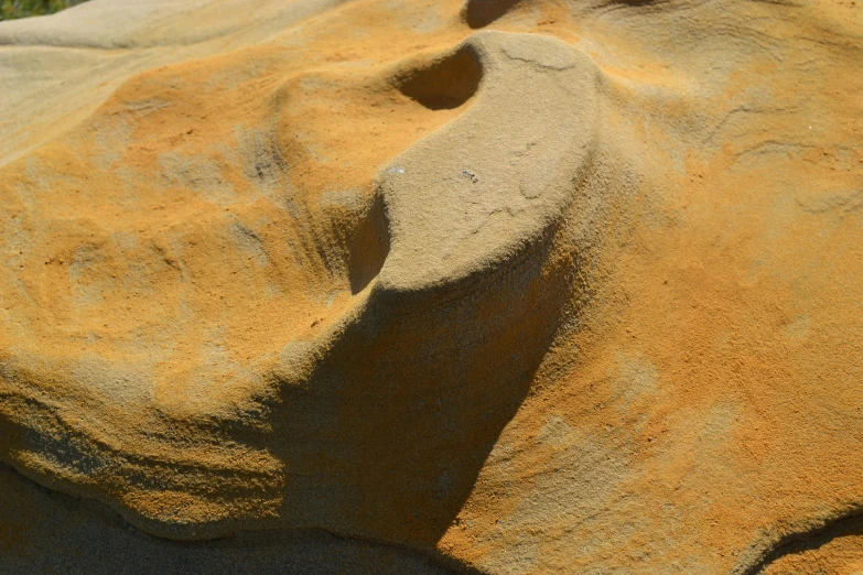 a bird sitting on top of a large rock, an abstract sculpture, by Doug Ohlson, unsplash, land art, sand color, ochre, face in detail, ( ( ( ( kauai ) ) ) )