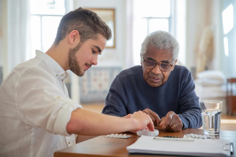 two men sitting at a table looking at a laptop, by Washington Allston, pexels contest winner, renaissance, acupuncture treatment, two aboriginal elders, board games on a table, nursing home