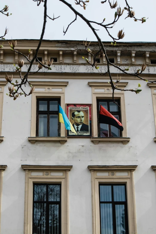 a building with a flag hanging on the side of it, a photo, inspired by Leon Wyczółkowski, socialist realism, black and yellow and red scheme, both faces visible, andrzej duda, at home