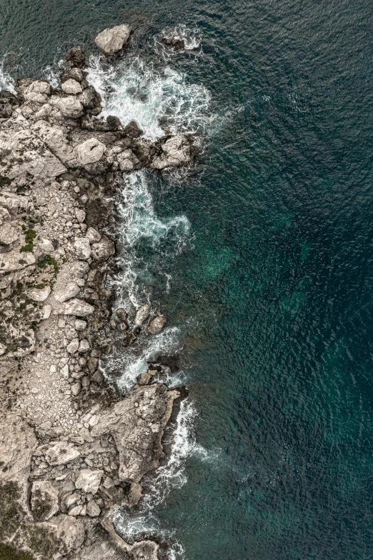 a large body of water next to a rocky shore, trending on pexels, top down camera angle, mediterranean features, 8 k detailed photograph, light and dark