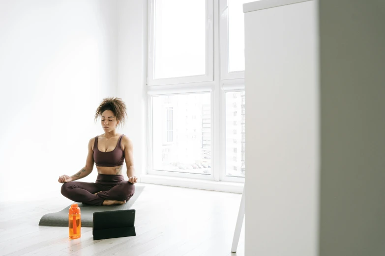 a woman sitting on a yoga mat in front of a window, pexels contest winner, in a white room, profile image, manuka, ashteroth