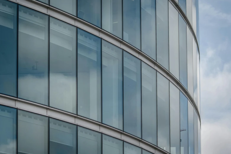 a clock that is on the side of a building, inspired by Richard Wilson, unsplash, bauhaus, large glass windows, stacked image, curved lines, shades of blue and grey