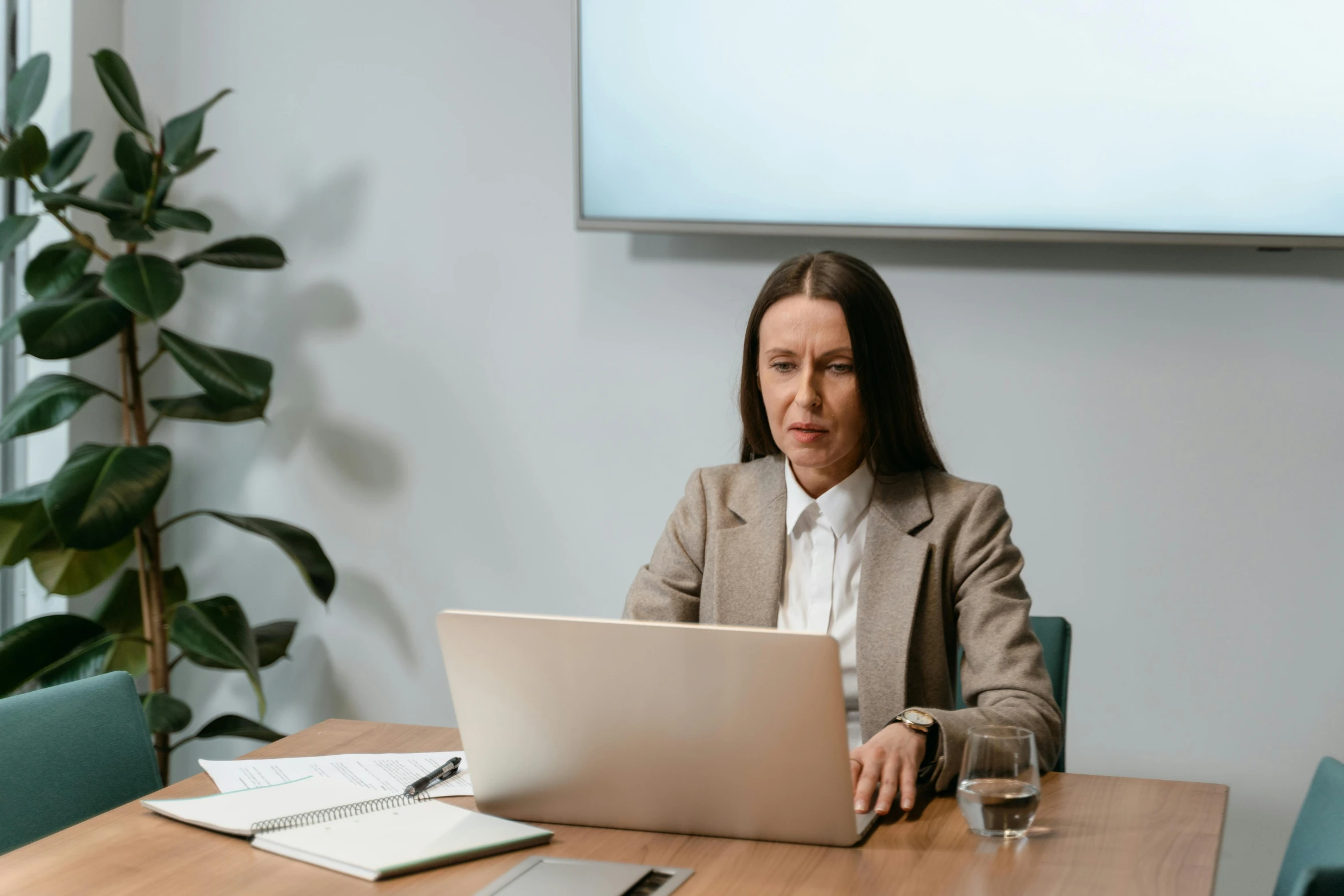 a woman sitting at a table with a laptop, slightly pixelated, corporate boss, brown, abcdefghijklmnopqrstuvwxyz