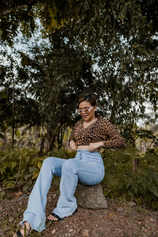 a woman sitting on top of a tree stump, trending on pexels, wearing a shirt and a jean, wearing animal skin clothing, colombian, thick rimmed glasses